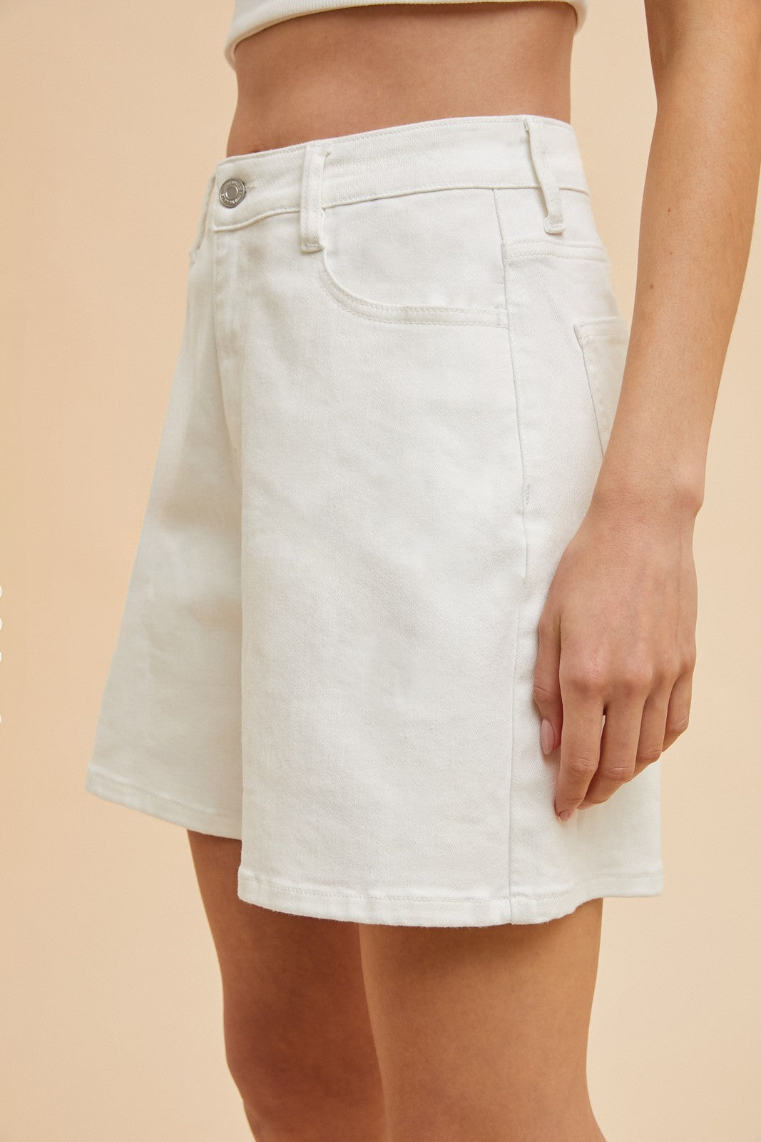 White denim skirt worn by a person on a beige background