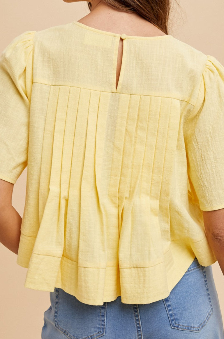 Woman wearing a yellow blouse with a beige background