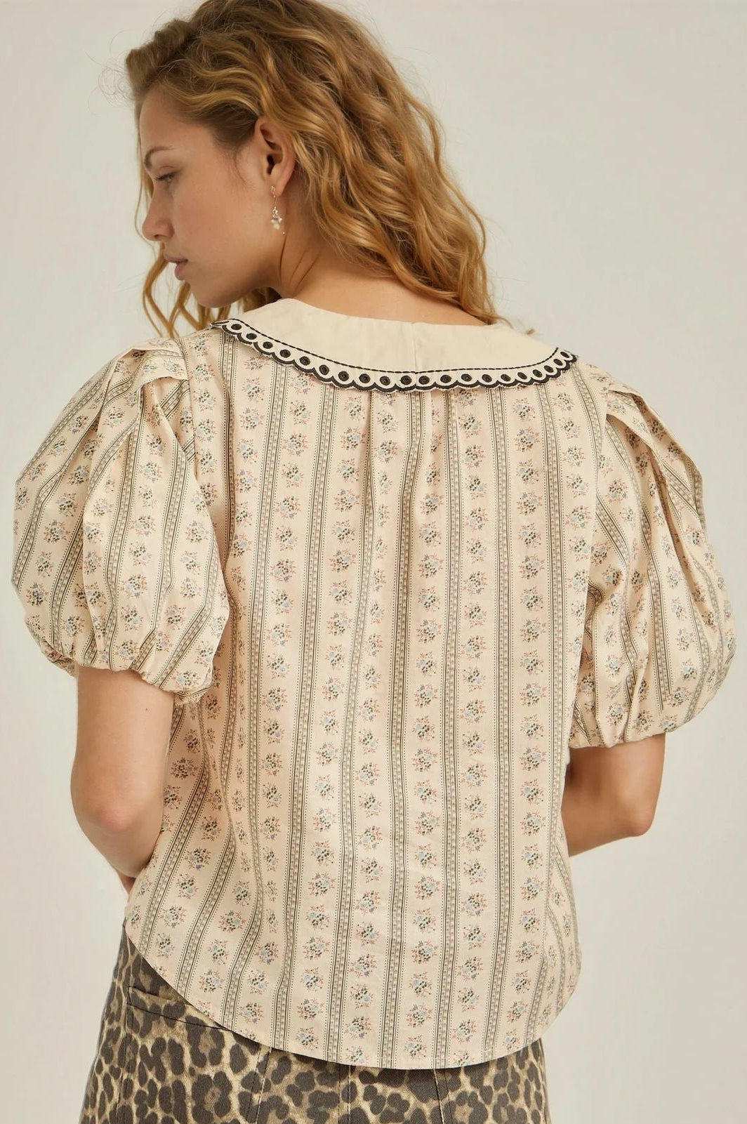Woman wearing a patterned top and leopard print shorts on a plain background