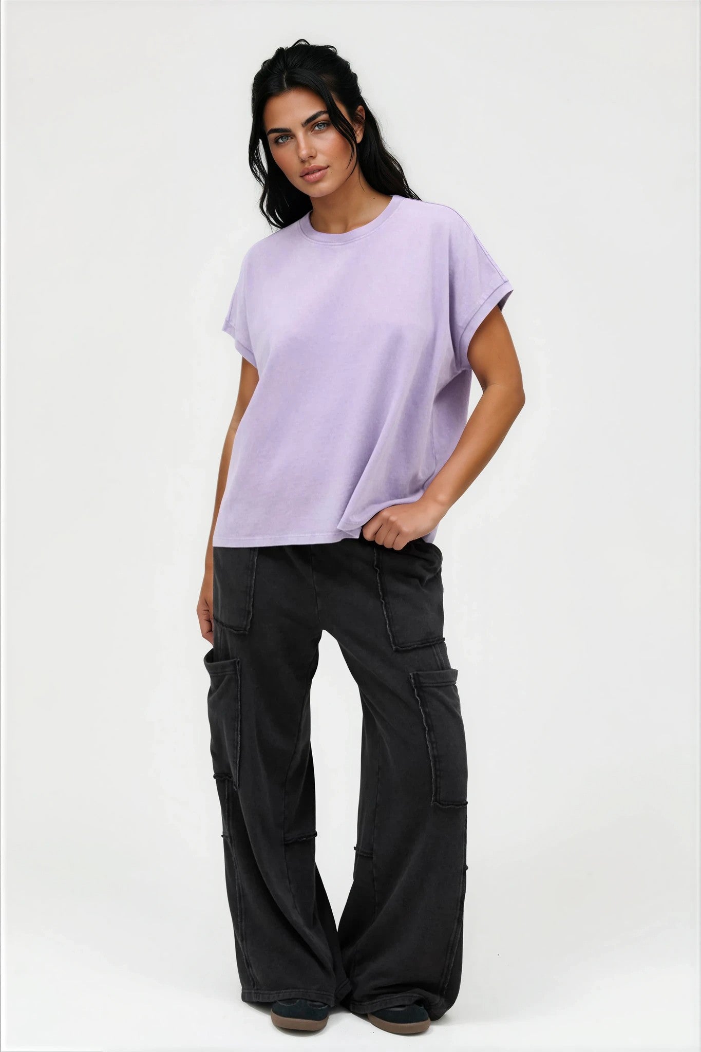 Woman wearing a light purple t-shirt and black cargo pants on a white background