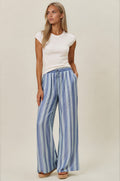Woman wearing a white top and blue striped pants on a beige background