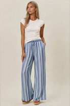 Woman wearing a white top and blue striped pants on a beige background