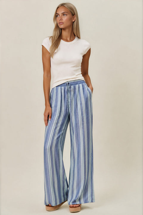 Woman wearing a white top and blue striped pants on a beige background