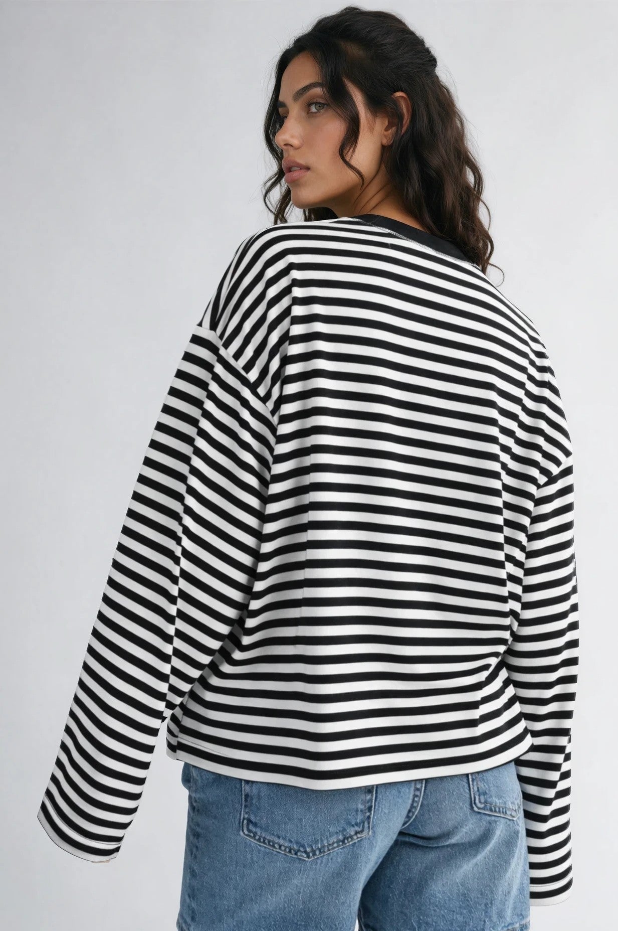 Person wearing a black and white striped sweater and denim shorts on a plain background